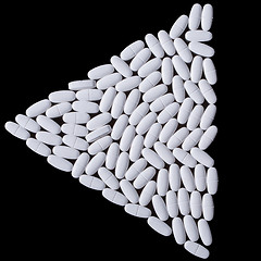 Image showing White pills on the black. Triangle of tablets.