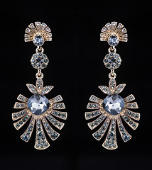 Image showing gold earrings with jewels on the black