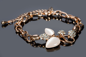 Image showing gold bracelet on gray background. 