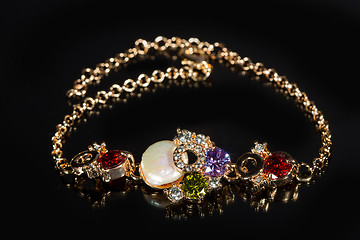 Image showing golden bracelet with precious stones on black background