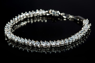 Image showing silver bracelet with diamonds on black background. 