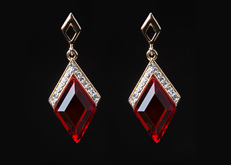 Image showing earring with colorful red gems on black background