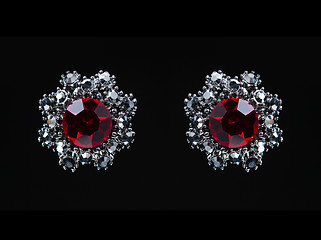 Image showing earring with colorful red gems on black background