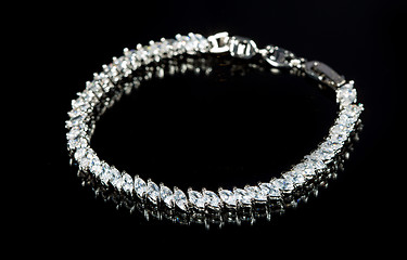 Image showing silver bracelet with diamonds on black background. 