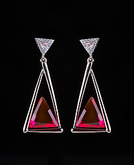 Image showing earring with colorful red gems on black background