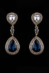 Image showing earring with colorful blue gems on black background