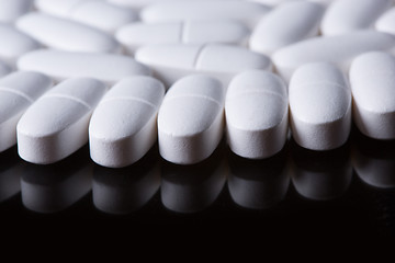 Image showing White pills on the black