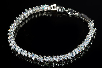 Image showing silver bracelet with diamonds on black background. 