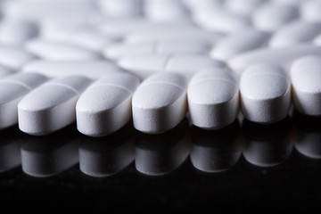 Image showing White pills on the black