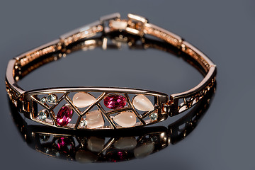 Image showing golden bracelet with precious stones on grey background