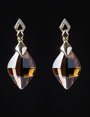 Image showing gold earrings with jewels on the black