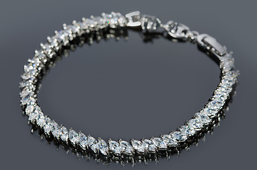 Image showing silver bracelet with diamonds on gray background. 