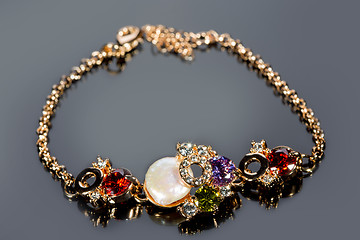 Image showing golden bracelet with precious stones on grey background