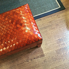 Image showing Orange leather bench on wooden floor