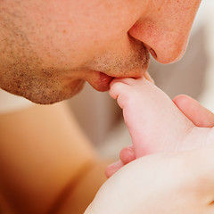 Image showing father kisses the foot of baby.