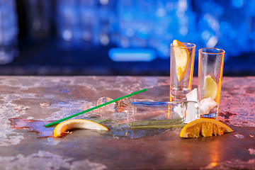 Image showing The spilled cocktails with ice cubes on blue color in the bar