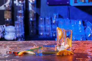 Image showing The spilled cocktails with ice cubes on blue color in the bar