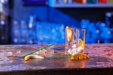 Image showing The spilled cocktails with ice cubes on blue color in the bar