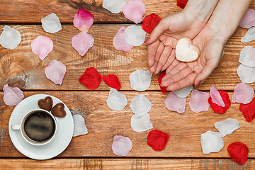 Image showing Valentines Day concept.  Female hands with  hearts on wooden background 