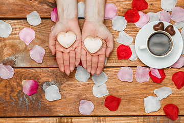 Image showing Valentines Day concept.  Female hands with  hearts on wooden background 