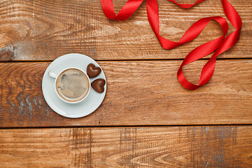 Image showing The red  ribbon on  wooden background with a cup of coffee