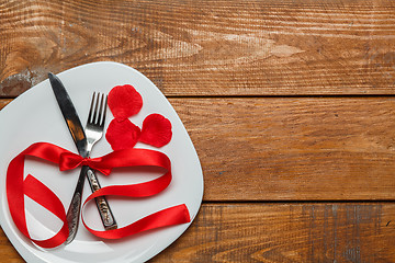 Image showing The red ribbon in plate on wooden background