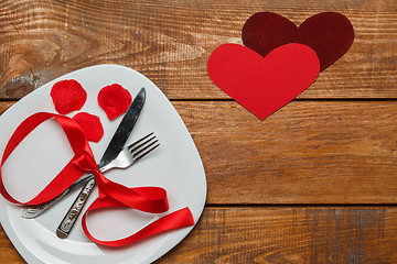 Image showing The ribbon in plate on wooden background with a heart