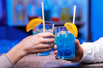 Image showing The hands with alcohol cocktails making toast on a bar background