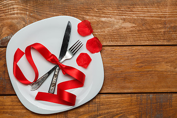 Image showing The red ribbon in plate on wooden background