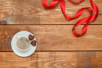 Image showing The red  ribbon on  wooden background with a cup of coffee