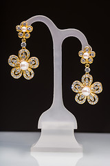 Image showing gold earrings with white little stones. in the form of flowers