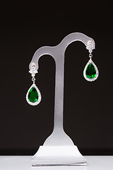 Image showing earrings with green stones on a stand