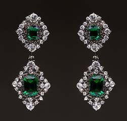 Image showing earrings with green stones on the black 