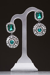 Image showing earrings with green stones on a stand