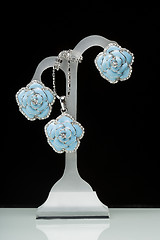 Image showing earrings with blue stones on the black. flowers