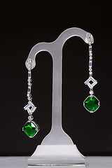 Image showing earrings with green stones on a stand