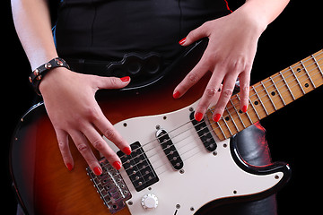 Image showing female hand on the detail of a guitar in dark back. Rock star 