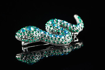 Image showing brooch in the form of a snake. green stones. black background