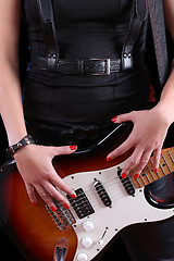 Image showing female hand on the detail of a guitar in dark back. Rock star 