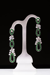Image showing earrings with green stones on a stand