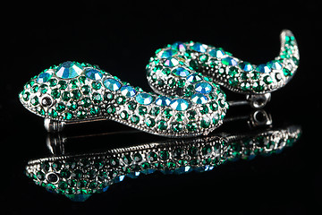 Image showing brooch in the form of a snake. green stones. black background