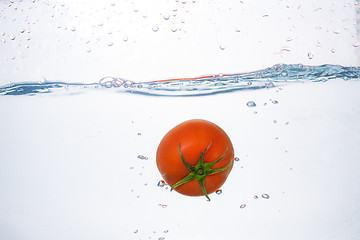 Image showing red tomato dropped into blue water on white