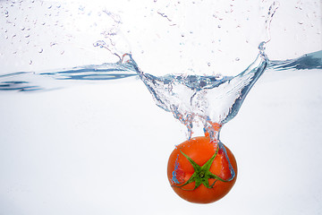 Image showing red tomato dropped into blue water on white