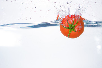 Image showing red tomato dropped into blue water on white