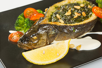 Image showing Stuffed seabass on a black plate 