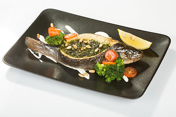 Image showing Stuffed seabass on a black plate 