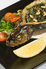 Image showing Stuffed seabass on a black plate 