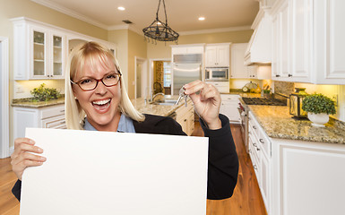 Image showing Young Woman Holding Blank Sign and Keys Inside Kitchen