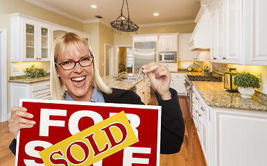 Image showing Young Woman Holding Sold Sign and Keys Inside New Kitchen