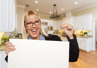 Image showing Young Woman Holding Blank Sign and Keys Inside Kitchen